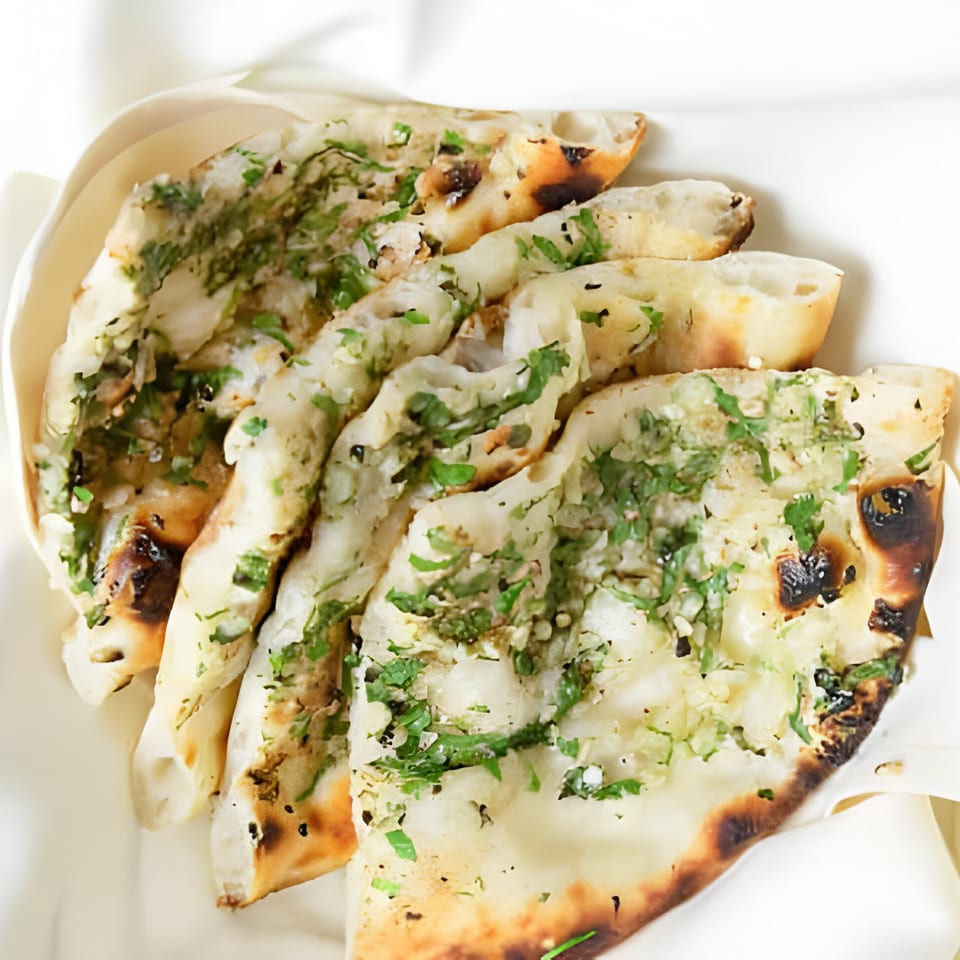 Close-up of several pieces of PIND Indian Cuisine's garlic naan, garnished with fresh cilantro.