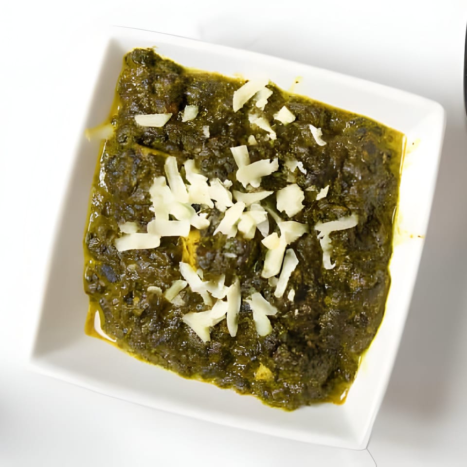 PIND Indian Cuisine's Palak Paneer, a spinach and cheese dish, served in a white square bowl.